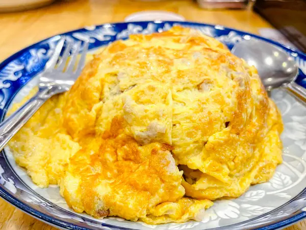 Tahta masadaki beyaz tabakta pilavlı omlet.