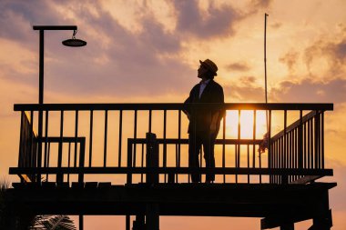 Genç Asyalı kadın gün batımında iskelede vakit geçiriyor. 