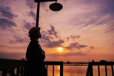 Gün batımının doğa manzarası, rıhtımda duran kadın.