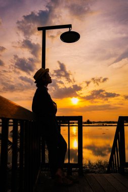 Gün batımının doğa manzarası, rıhtımda duran kadın.