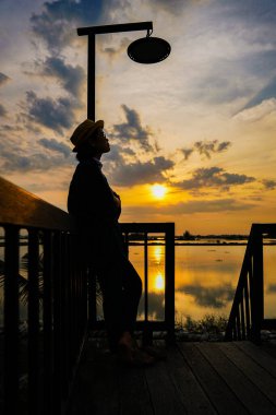 Gün batımında iskelede oturan kadın.