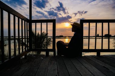 Gün batımının doğa manzarası, rıhtımda duran kadın.