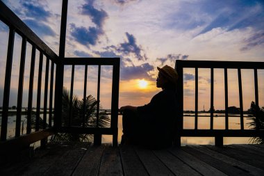 Gün batımının doğa manzarası, rıhtımda duran kadın.