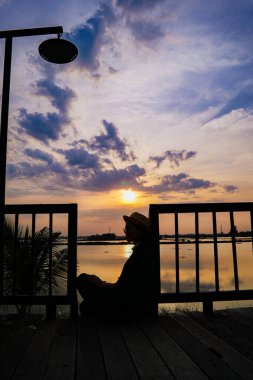 Gün batımında iskelede oturan kadın.