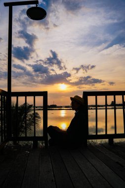 Gün batımında iskelede oturan kadın.