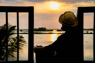 Gün batımının doğa manzarası, rıhtımda duran kadın.