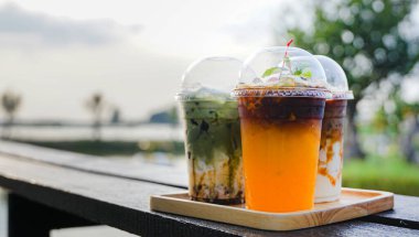 Bir bardak buzlu kahveyi portakal suyuyla kapat, buzlu kibrit yeşil çay ve buzlu çikolata bir kahve dükkanının yaz terasında, menü fotoğrafçılığı..