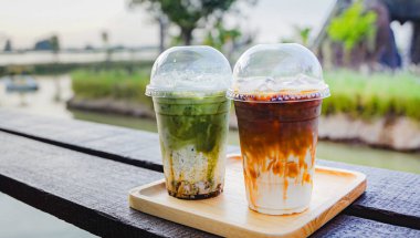 Yakın çekim ve seçici odaklı buzlu kibrit latte ve ahşap masada buzlu kahve sütü..