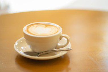 Tahta masada beyaz bir fincanda sütlü kahvenin yan görüntüsü.