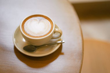 Sütlü kahvenin üstünde, latte sanatı ve ahşap bir masada.