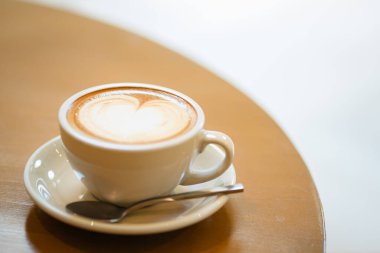 Sütlü kahvenin üstünde, latte sanatı ve ahşap bir masada.