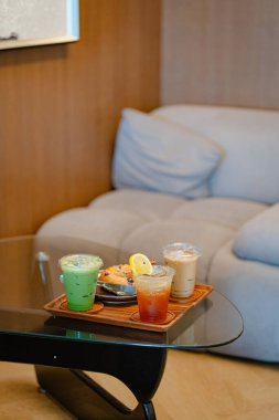 Kafedeki cam masada espresso tonik, buzlu latte ve buzlu kibrit gibi içecekler var.