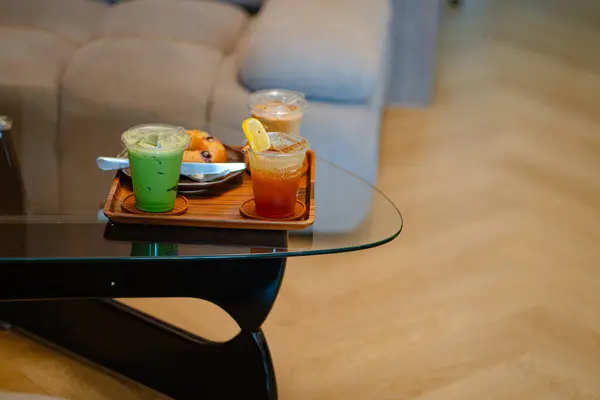 Kafedeki cam masada espresso tonik, buzlu latte ve buzlu kibrit gibi içecekler var.