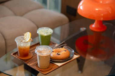 Kafedeki cam masada espresso tonik, buzlu latte ve buzlu kibrit gibi içecekler var.