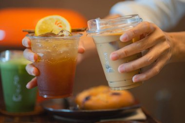 Bir kadının elinde limon dilimi ve tarçın çubuğu ve buzlu latte ile ekilmiş espresso toniği. 