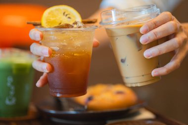 Bir kadının elinde limon dilimi ve tarçın çubuğu ve buzlu latte ile ekilmiş espresso toniği. 