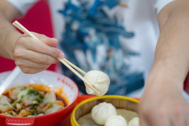 Bulaşıkların yanında çubuklarla hamur köftesi tutan kişi.