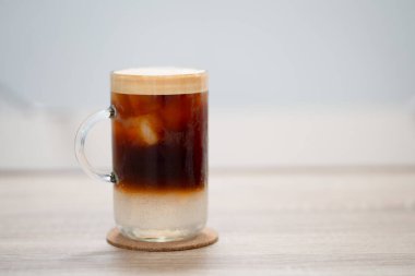 Masanın üzerinde cam bardakta buzlu kahve.