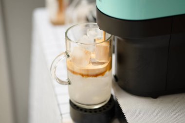 Kahve makinesi cam bardakta buzlu latte yapıyor.