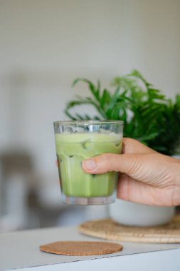 Bir el buzlu soğuk yeşil bir içecek tutar..