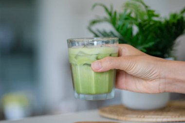 Bir el buzlu soğuk yeşil bir içecek tutar..