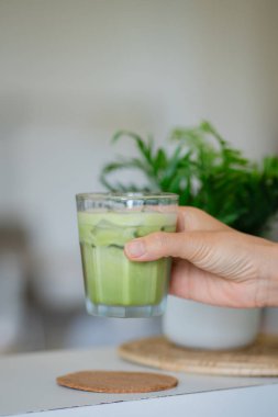 Bir el buzlu soğuk yeşil bir içecek tutar..