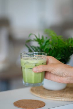 Bir el buzlu soğuk yeşil bir içecek tutar..