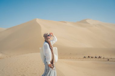 Kum tepeciğinde tesettür ve güneş gözlüğü takan bir kadın..
