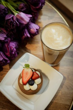Sıcak kapuçino, kek ve kafedeki masada laleler. Yüksek kalite fotoğraf