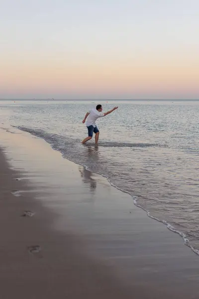 Genç adam güneşin doğuşuna karşı deniz kenarında yürüyordu. Fujairah, BAE. Yüksek kalite fotoğraf