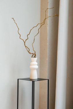 Minimalist köşesinde siyah minimalist kaidede kurumuş dalları olan beyaz seramik vazo. Yüksek kalite fotoğraf