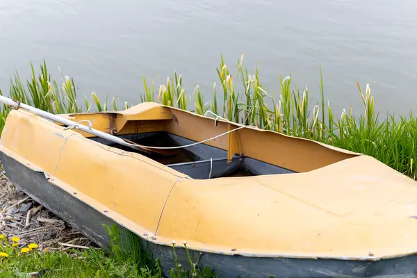 Gölün kıyısındaki çimlerin üzerinde eski bir tekne var. Yüksek kalite fotoğraf