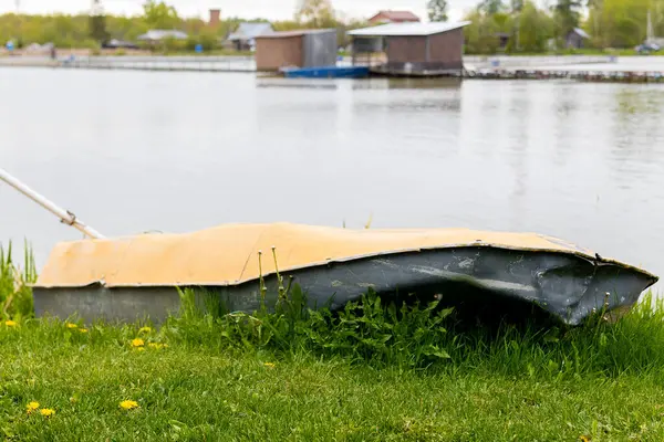 Gölün kıyısındaki çimlerin üzerinde eski bir tekne var. Yüksek kalite fotoğraf