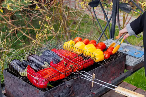 Bir adam taze sebzeleri ızgaranın üstüne ızgaranın içine koyar. Yüksek kalite fotoğraf