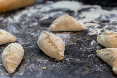 Patates ve mantarlı turta yapma süreci. Kalıplı turtalar koyu bir masada, un içinde yatıyor. Yüksek kalite fotoğraf
