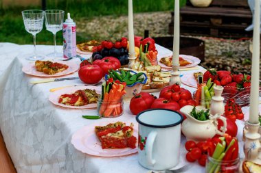 Bahçede bekarlığa veda partisi için güzel romantik bir dekor. Masa mumlar, domatesler ve çiçeklerle süslenmiş. Yüksek kalite fotoğraf