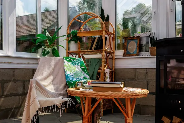 Kapalı verandada rahat bir köşe: ahşap bir soba, etrafta rattan mobilyalar. Yerde bir halı. Sandalyenin üzerine battaniye atılmış. Yüksek kalite fotoğraf