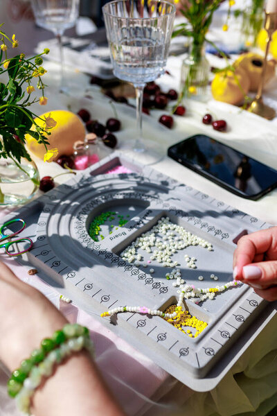 Hobby concept.Top view of artistic female hands creating beaded bracelet. High quality photo