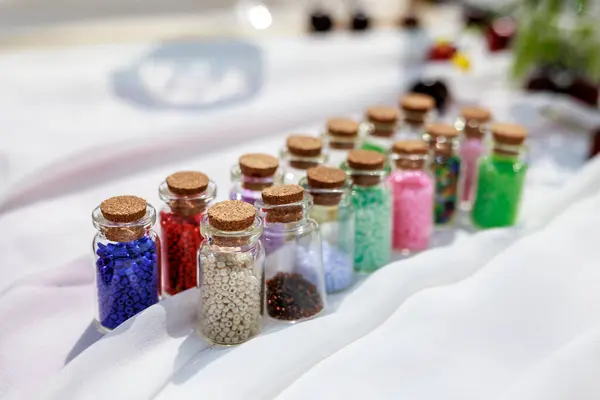 Hobi konsepti. Boncukları saklamak için mantarlı cam kavanozlar. Boncuklar renklerine göre sıralanmış. Yüksek kalite fotoğraf