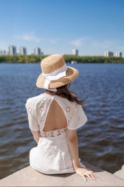 Beyaz elbiseli ve şapkalı sarışın sıska kız rıhtımda poz veriyor. Yüksek kalite fotoğraf