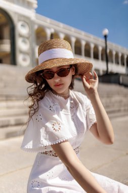 Nehir istasyonunun merdivenlerinde şapkalı ve beyaz elbiseli bir kız oturuyor. Yüksek kalite fotoğraf