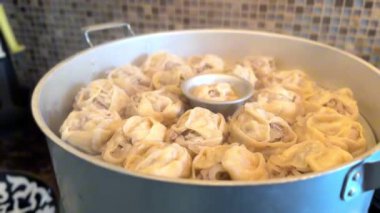 Manti, geleneksel Özbek buhar tenceresinde ev gazı sobasında pişirilir. Yakın plan çekim. Yüksek kaliteli FullHD görüntüler