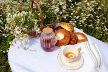 Pastalarla çay, çaydanlık çay, bir fincan ve papatya tarlasında bir sepet papatya. Yüksek kalite fotoğraf