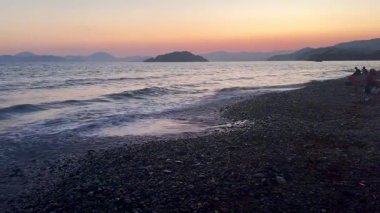 Akdeniz 'in karanlık ve sakin yüzeyinde altın gün batımı gökyüzü. Gün batımına karşı ağır çekimde hareket eden resim gibi dalgalar. Yüksek kaliteli FullHD görüntüler