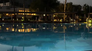 Geceleri Fethiye tatil beldesindeki havuzun sakin sularına binalar, dinlenme yerleri ve bebek arabaları yansıtılıyor. Yüksek kaliteli FullHD görüntüler