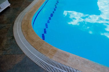 Kenarlarında kahverengi fayanslar olan mavi bir yüzme havuzunun üst görüntüsü. Dikey yakın plan fotoğraf. Yüksek kalite fotoğraf