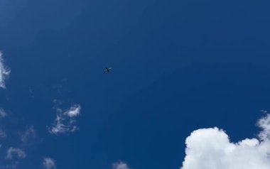 Büyük yeşil bir yolcu uçağı beyaz kabarık bulutların arasında gökyüzünde uçar. Yüksek kaliteli HD görüntüler