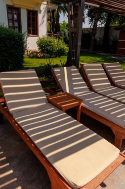 Yüzme havuzunun yanında boş güneş pansiyonları, tropik bir tatil beldesindeki güvenlik çitinin kumaş gölgesiyle. Yüksek kalite fotoğraf