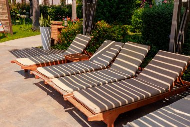 Yüzme havuzunun yanında boş güneş pansiyonları, tropik bir tatil beldesindeki güvenlik çitinin kumaş gölgesiyle. Yüksek kalite fotoğraf