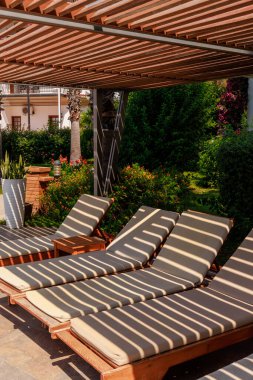 Yüzme havuzunun yanında boş güneş pansiyonları, tropik bir tatil beldesindeki güvenlik çitinin kumaş gölgesiyle. Yüksek kalite fotoğraf